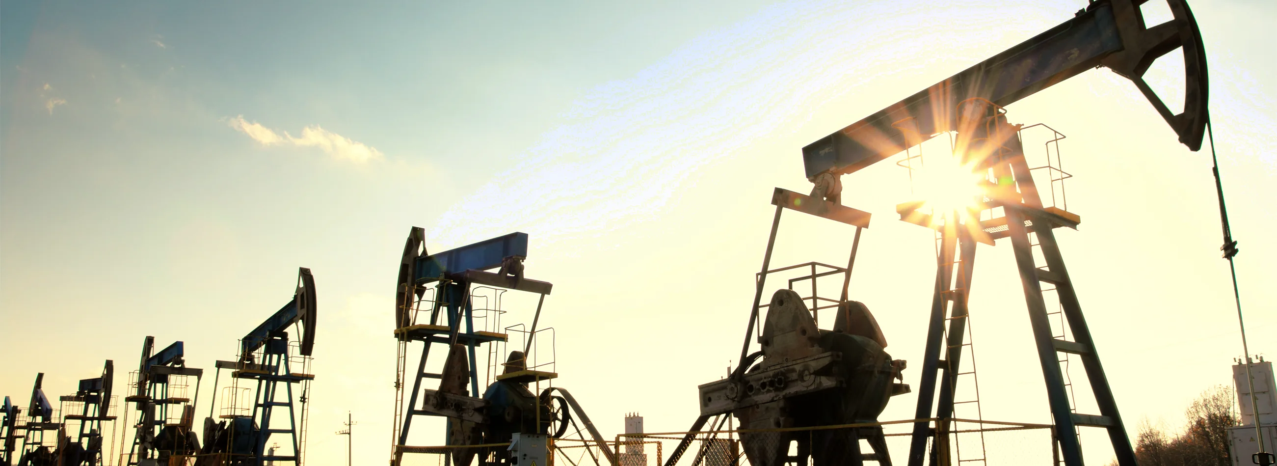 Oil pump jacks silhouetted against a low sun