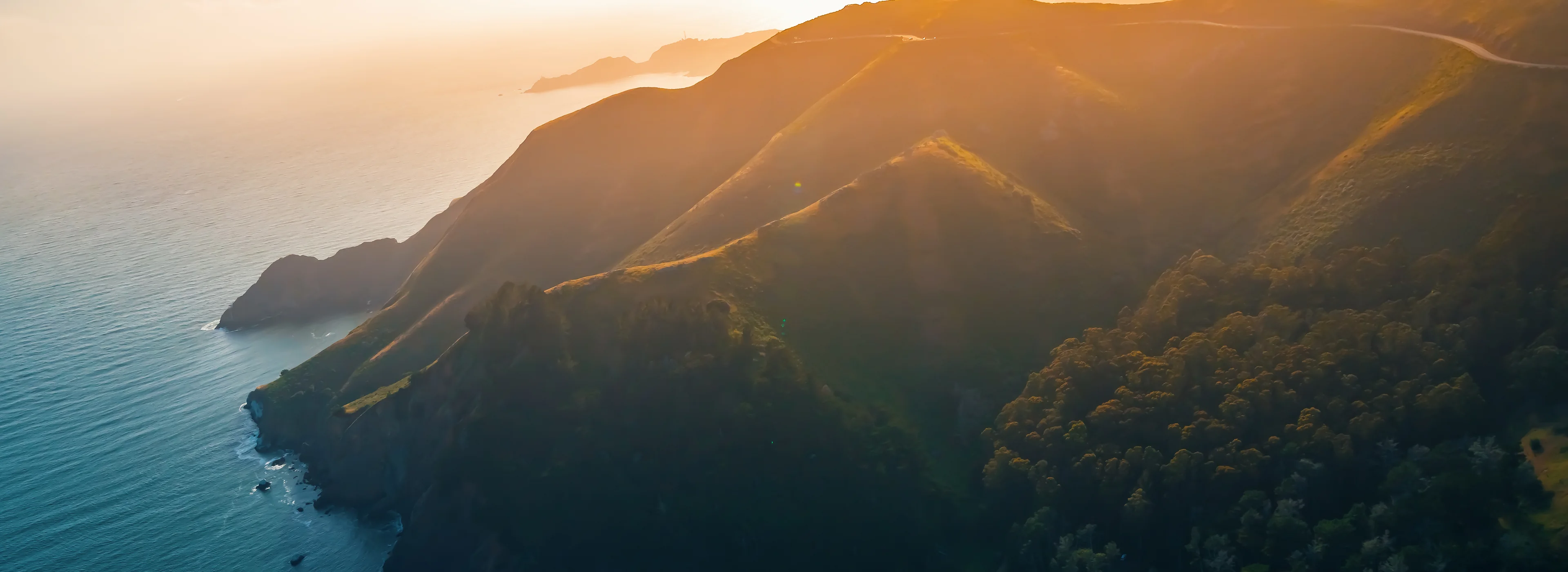 Coastal mountain ridges running down to the Pacific, backlit at sunset