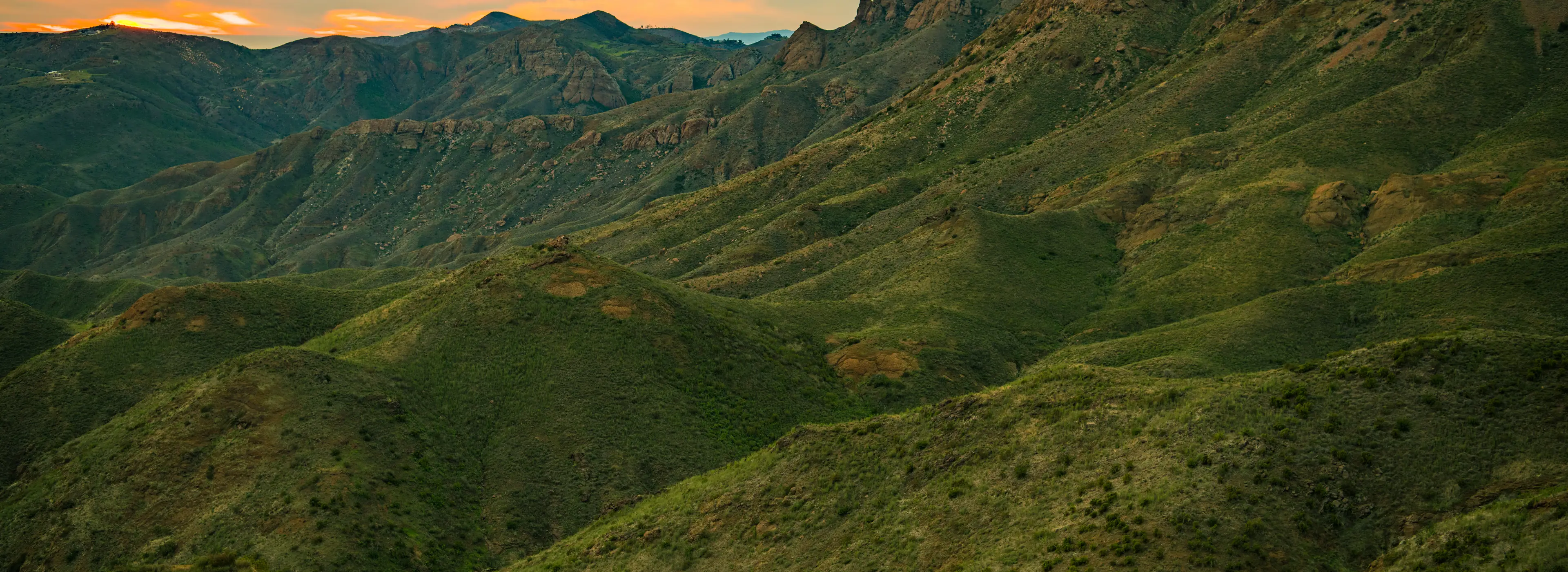Coastal mountain ridges above Malibu, ridge behind ridge, lit gold along the tops at sunset
